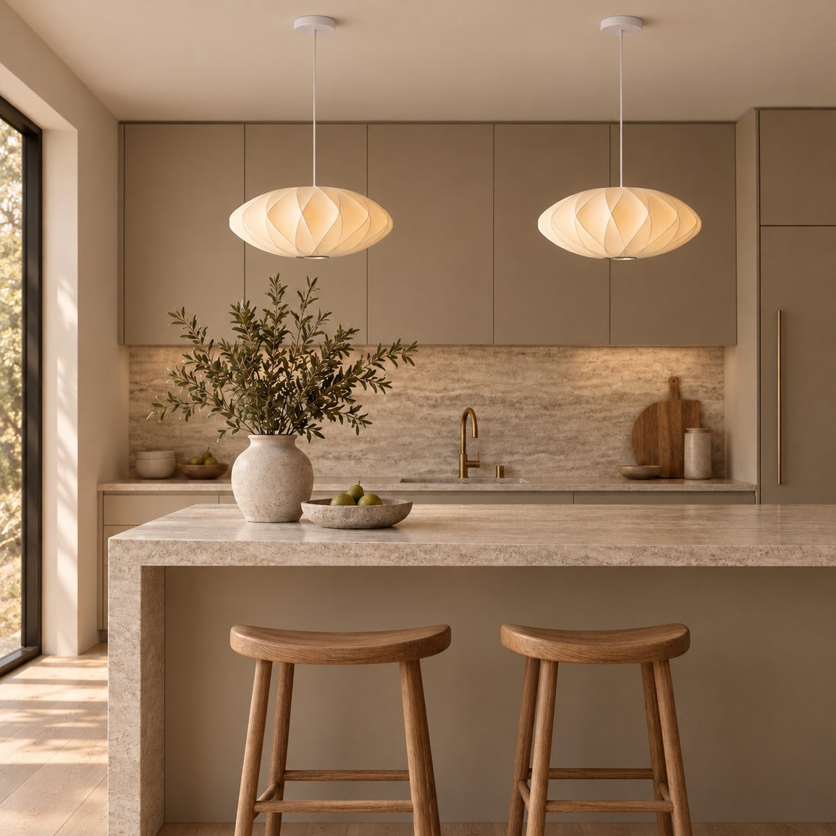 Two Corvya silk pendant lights above a stone kitchen island with wood stools and warm neutral cabinetry.