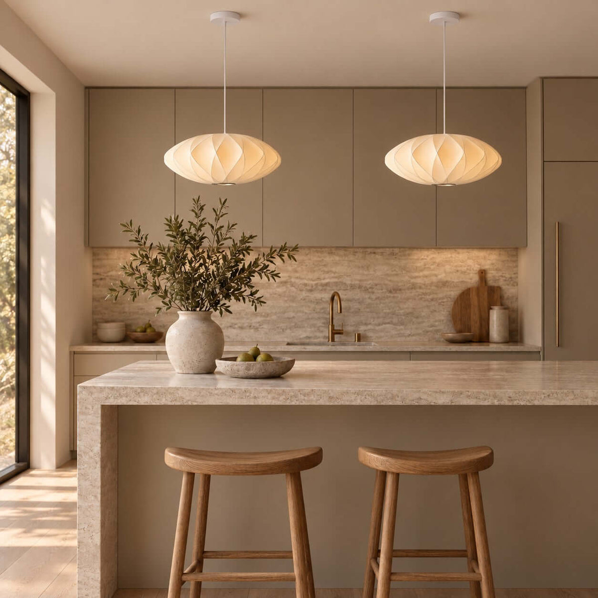 Two Corvya silk pendant lights above a stone kitchen island with wood stools and warm neutral cabinetry.