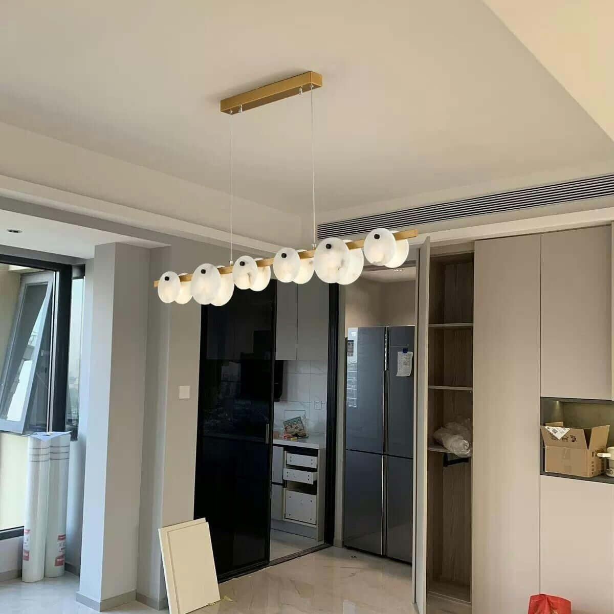 Frumix linear chandelier with alabaster shades, mid century modern design, enhancing bright kitchen interiors.