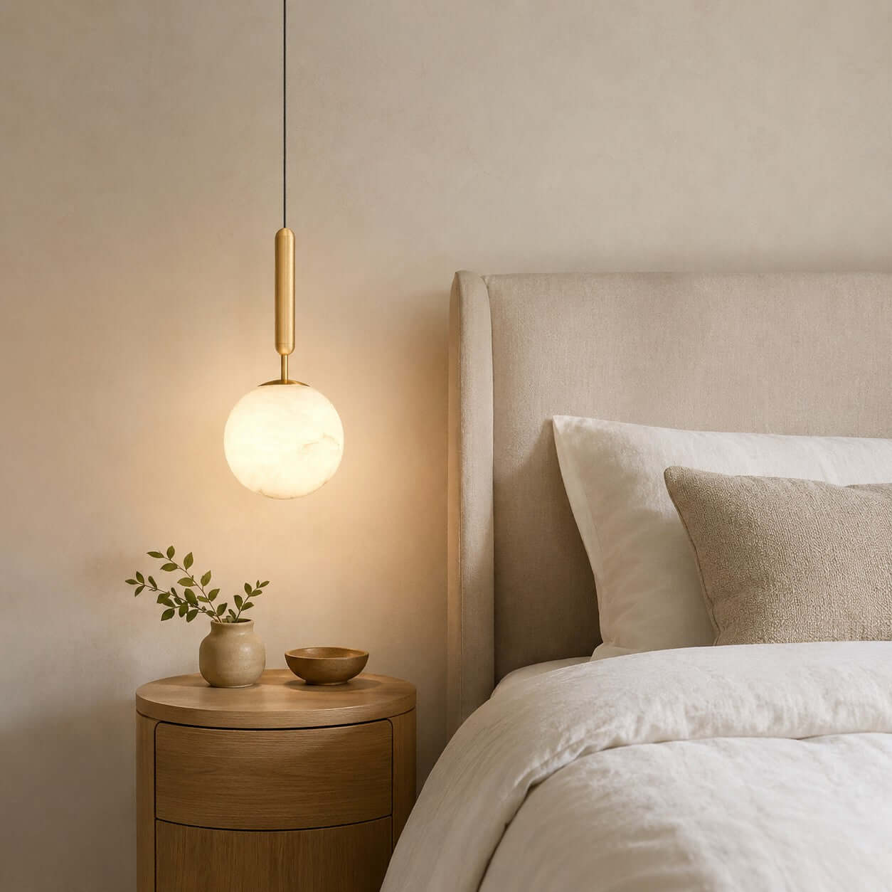 Small Velriq alabaster globe pendant light above a round nightstand beside a neutral bed