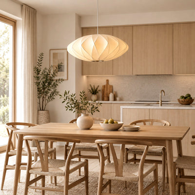 Corvya white silk pendant light above a rectangular wood dining table in an open-plan kitchen and dining room.