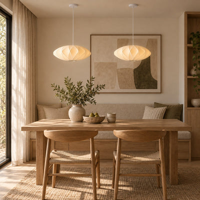 Two Corvya white silk pendant lights above a rectangular wood dining table with upholstered bench seating.