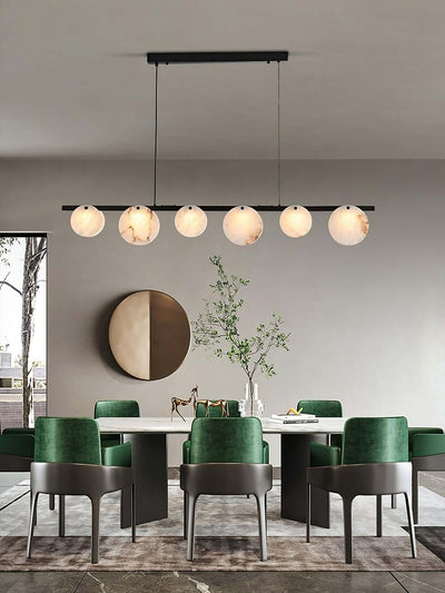 Frumix alabaster chandelier in a mid century modern dining room with green chairs and a round mirror decor.