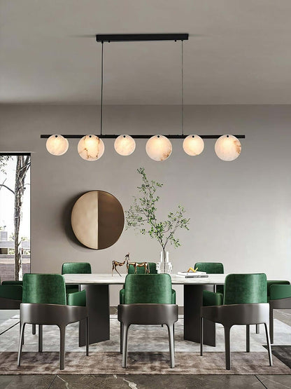 Frumix alabaster chandelier in a mid century modern dining room with green chairs and a round mirror decor.
