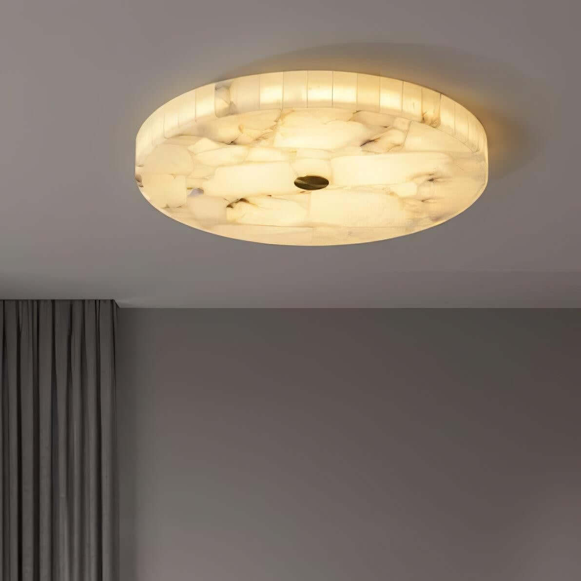 Round alabaster flush mount ceiling light illuminating a modern bedroom setting.