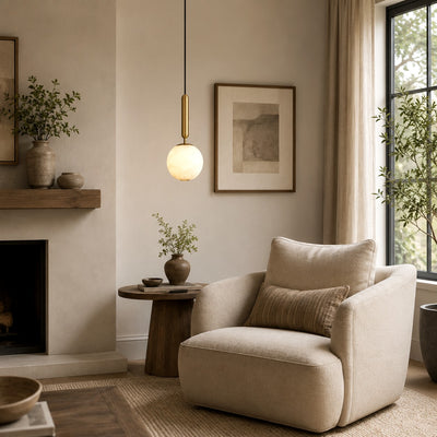 Velriq alabaster globe pendant light illuminating a neutral reading corner with an armchair